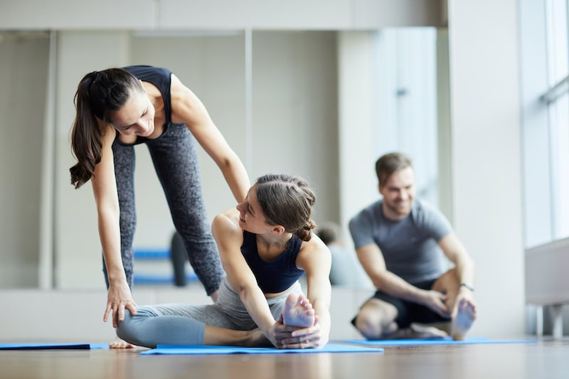 yoga teacher pushing back of student